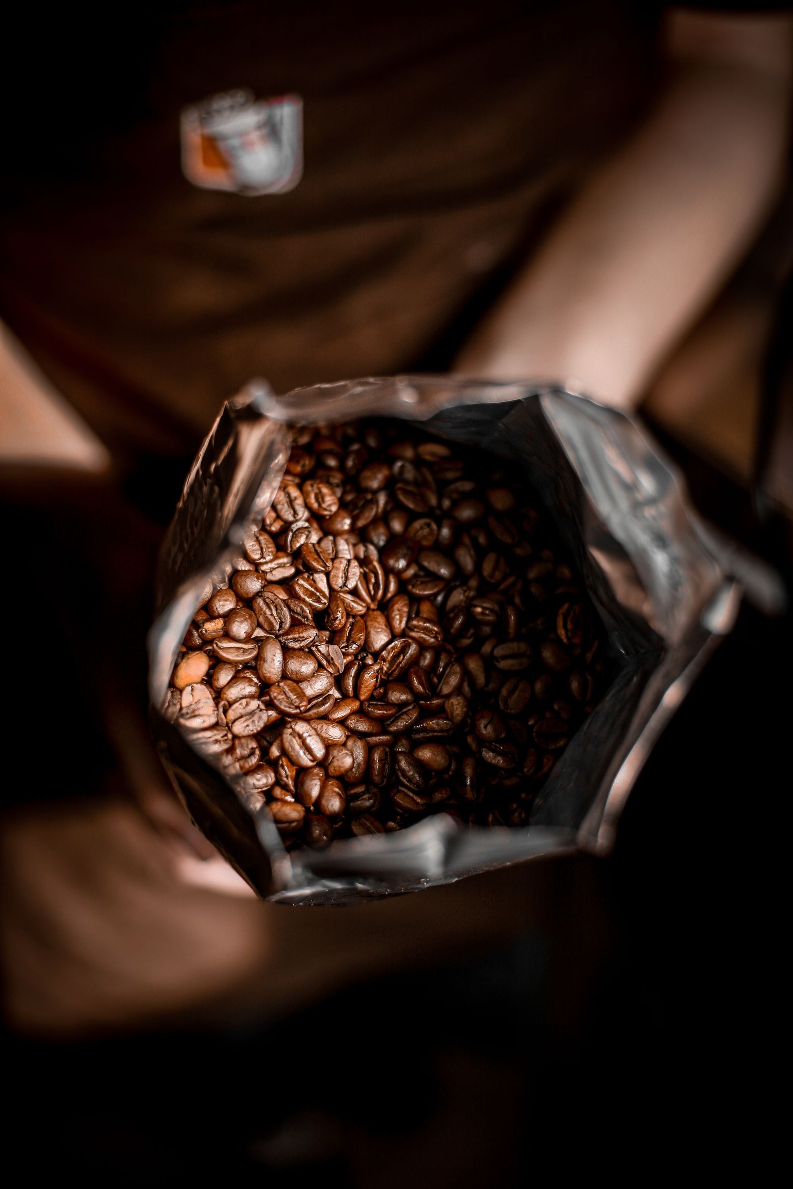 Persona mostrando granos de café dentro de un empaque flexible